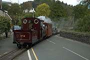 ‘Palmerston’ rolls across the road with a train of slate waggons.       (16/10/2005)